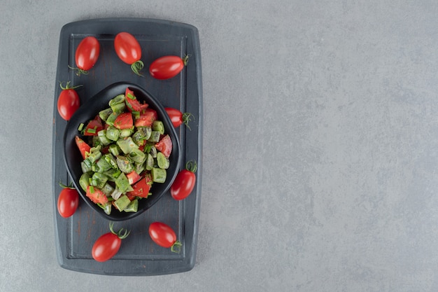 Red cherry tomato and beans salad on a black wooden board