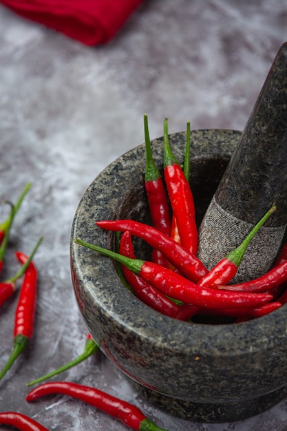 Free photo red chillies are in a stone mortar on black surface.