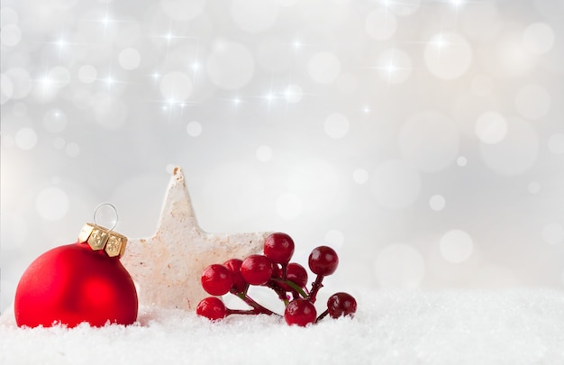 Free Photo red christmas ornament and holly shrub berries, and a white star on a snowy surface