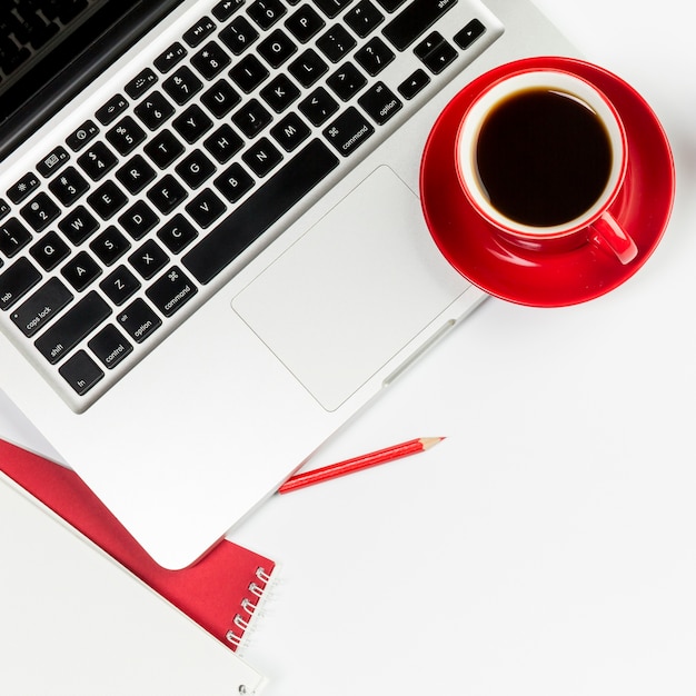 Red coffee cup on an open laptop over white background