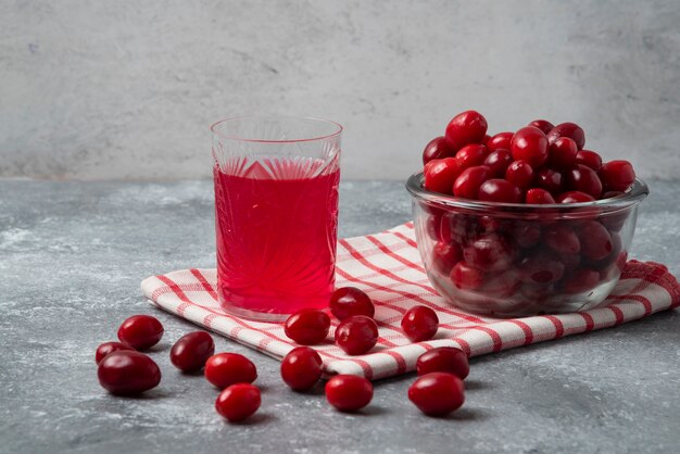 Red cornels in the glass cup on checked towel with a glass of juice.