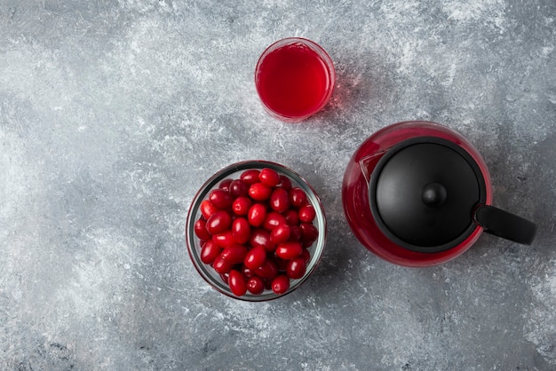 Red cornels in a glass cup with juice in the kettle and in the glass. 