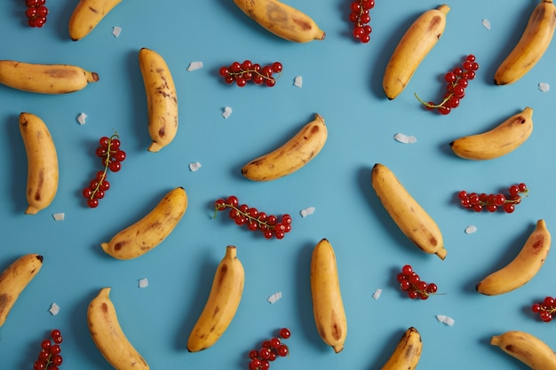 Free Photo red currant and yellow bananas for serving cakes, buns filling, making compotes, juice, homemade or smoothie. collection of exotic fruits and ripe berries. flat lay pattern. tasty summer fruits