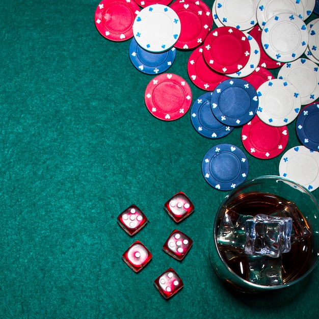 Red dices; casino chips and whisky glass on green poker table