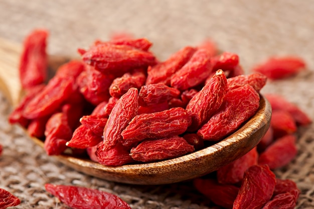 Red dried goji berries in wooden spoon