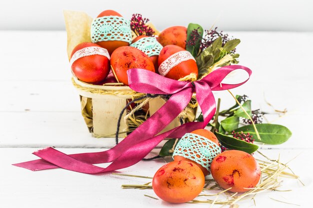 Red eggs tied lace tape, lying in an Easter basket with a bow