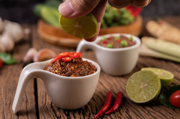 Red Eye Chili Paste with Lemon and Chili on Wooden Floor.