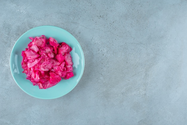 Red fermented sauerkraut on plate on the blue surface