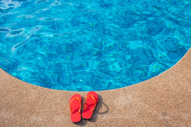 Free photo red flip flops next to the swimming pool