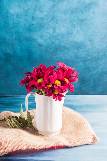 Free Photo red flowers in jug on canvas