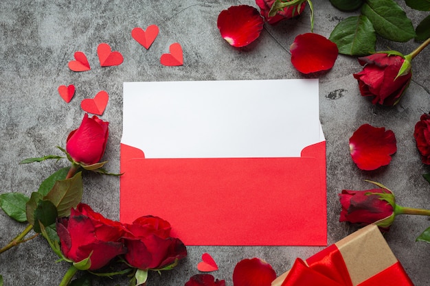 Red flowers of rose and envelop on dark background