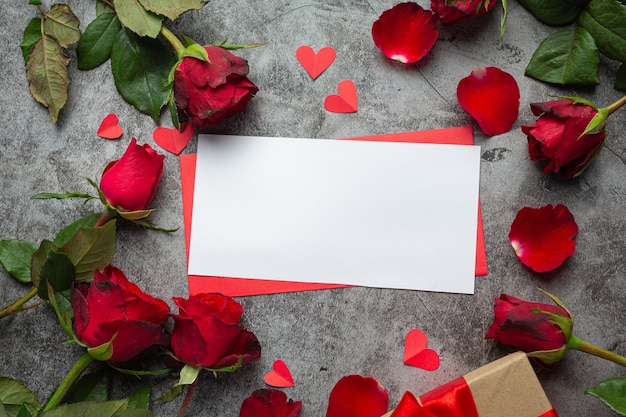 Red flowers of rose and envelop on dark background