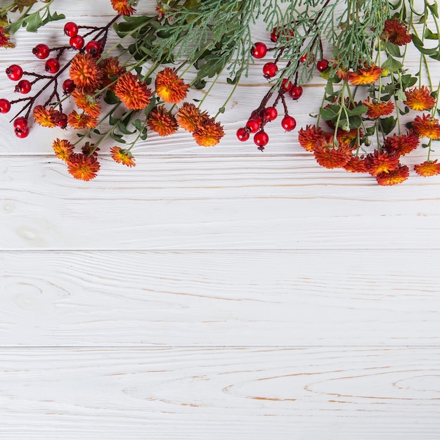 Red flowers with berries scattered on wooden table