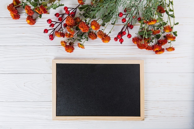 Free Photo red flowers with blank chalkboard on white table