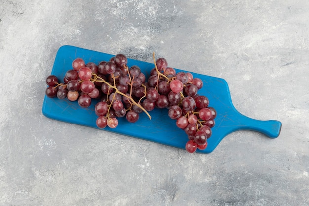 Free photo red fresh grapes placed on blue cutting board.