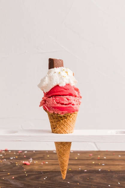 Red frozen ice scoop with with whipped cream and chocolate in cone