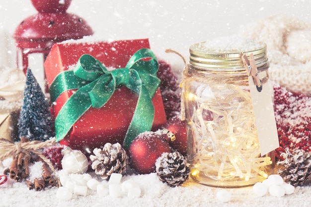 Red gift with green bow next to a glass jar with lights