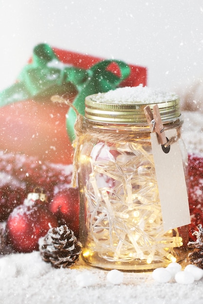 Free photo red gift with green bow next to a glass jar with lights