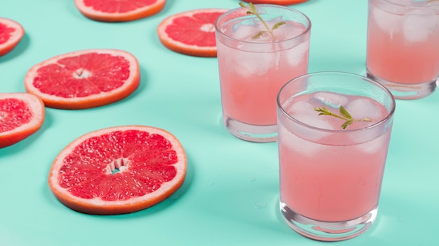 Free photo red grapefruit slices and cocktail juice on mint background