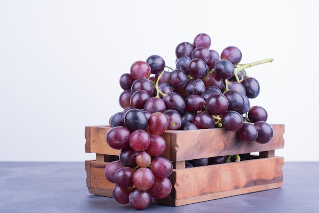 Red grapes in a wooden tray on blue surface