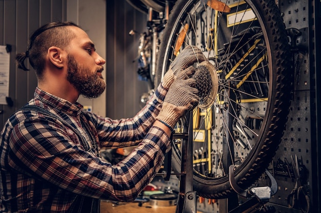 Free Photo red hair bearded mechanic removing bicycle rear cassette in a workshop.