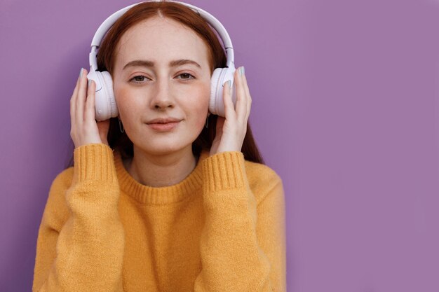 red hair young woman in cozy wear with headphones outdoor