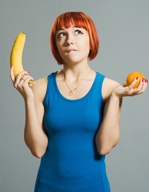 Red-haired girl with banana and orange