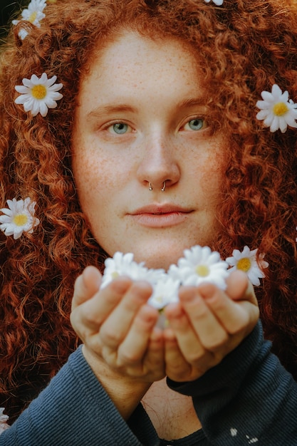 Free photo red-haired woman holding daisy flowers