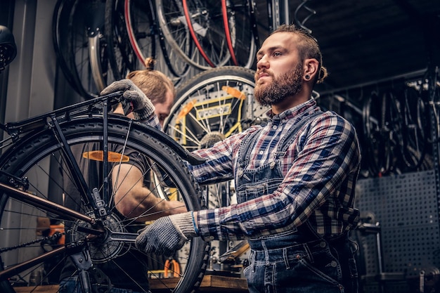 Free photo red head bearded mechanic fixing rear derailleur from a bicycle in a workshop.