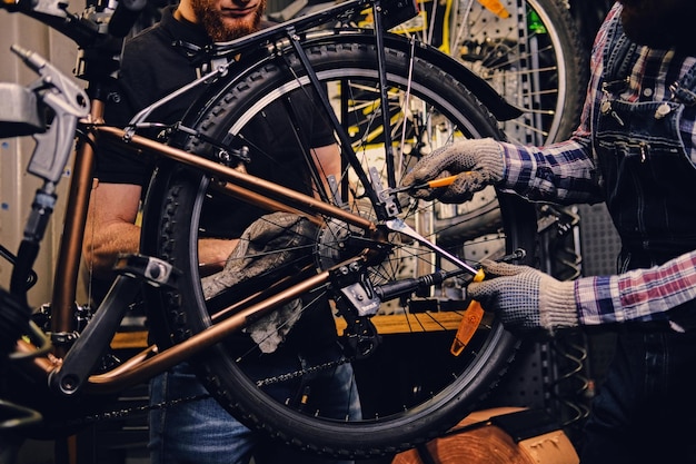 Free Photo red head bearded mechanic fixing rear derailleur from a bicycle in a workshop.