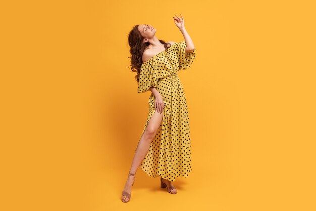 Red-head woman in yellow dress posing on yellow. Summer mood