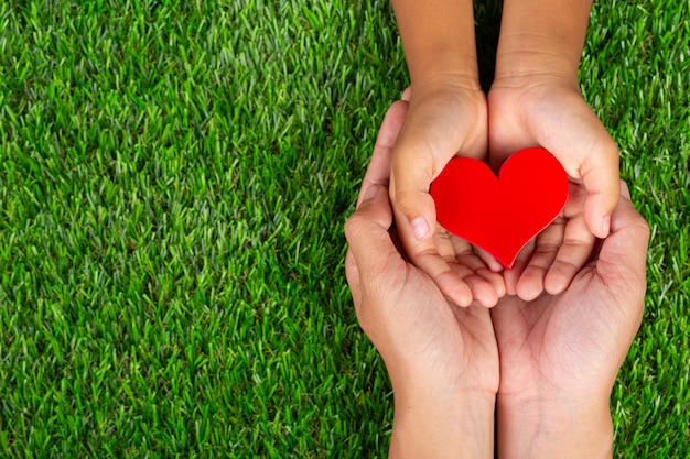 Red heart shape in family member's hands holding