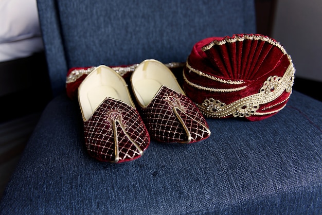 Free photo red indian's groom shoes and hat lie on the blue chair