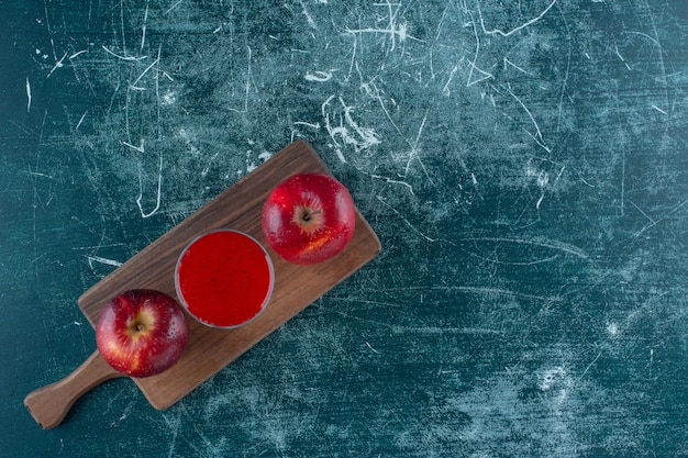 Red juice and apple on the board , on the blue background. High quality photo