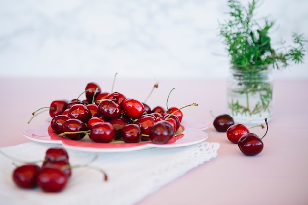 Free photo red juicy cherries on plate over pink desk