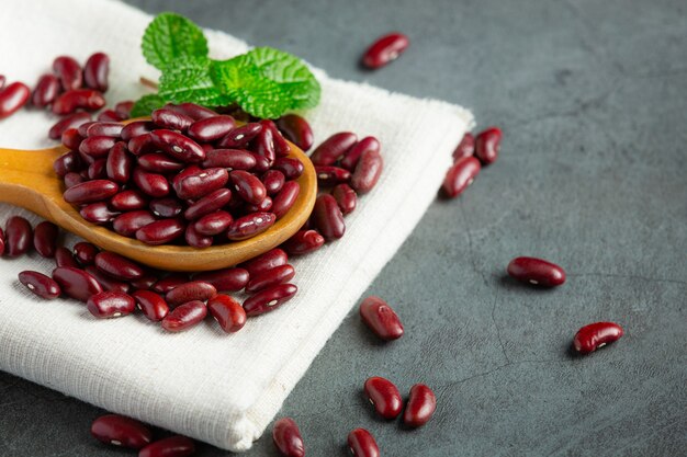 Red kidney beans in wooden plate spoon on white fabric