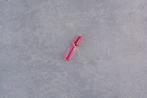 Free photo red medical ampoule on marble table.