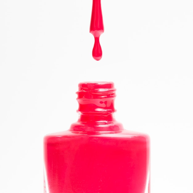 Free photo red nail polish dropping in its flask against a white background