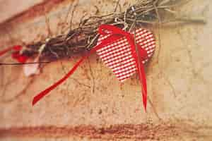 Free photo red ornament in the shape of a heart hanging on a branch