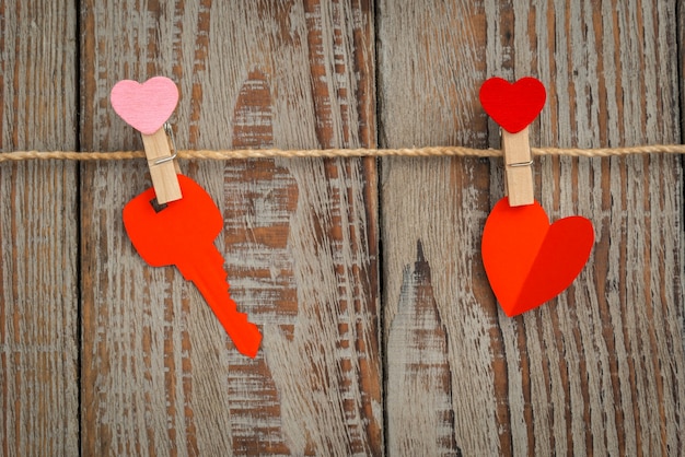 Red paper heart hanging on wood background .