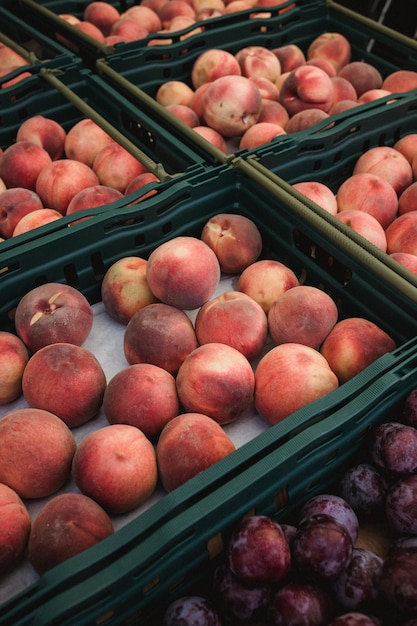 Red peach fruits in green basket close-up