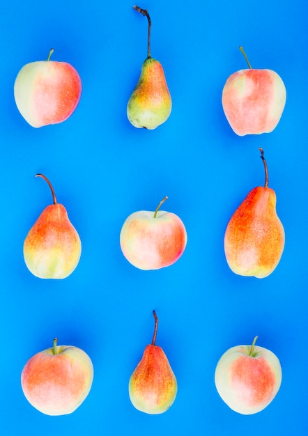 Free photo red and pear fruits on blue background