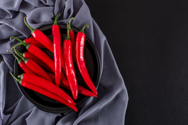 red pepper in black bowl on cloth on black surface