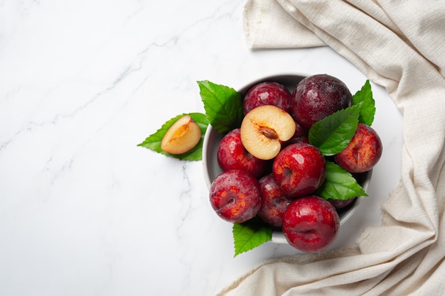 Free Photo red plum put in white bowl on white floor