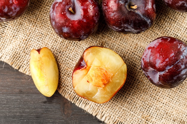 Free Photo red plums on grey and piece of sack surface, flat lay.