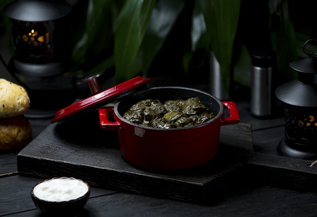 A red pot of local food yarpaq dolmasi, sarma on a dark board