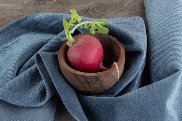 Red radish in wooden bowl with cloth