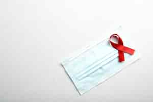 Free photo red ribbon and face mask with white background. hiv aids ribbon awareness