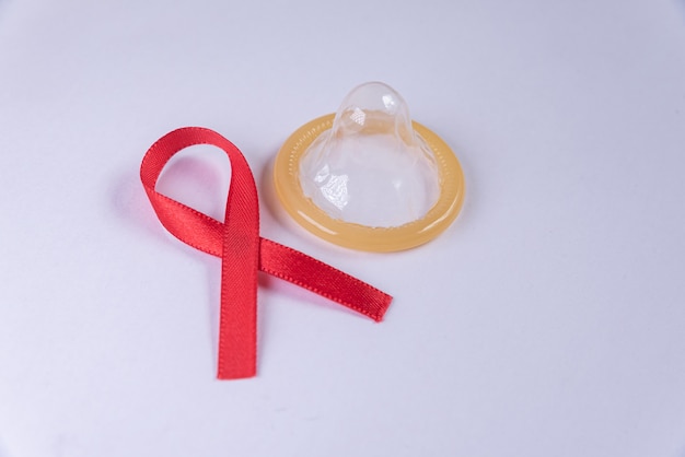 Free photo red ribbon and latex condom on the white table