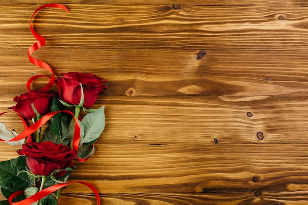 Red roses with ribbon on table